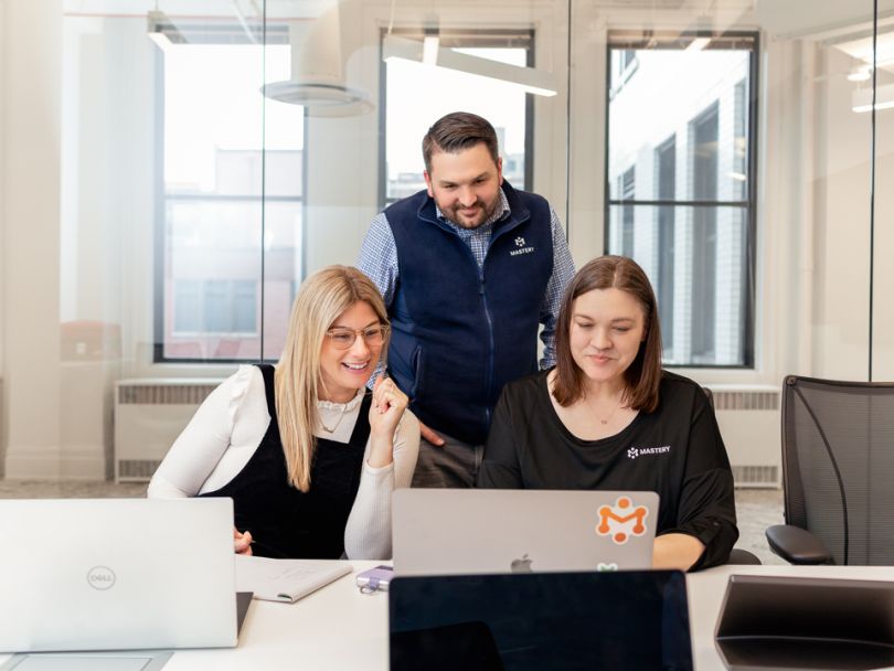 Tre impiegati in ufficio che esaminano un computer portatile