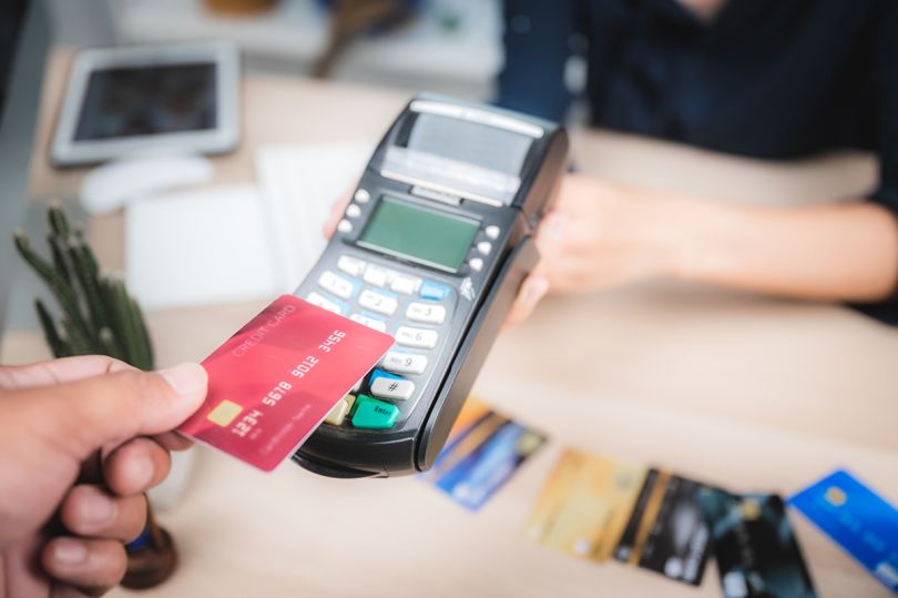 person holding a credit card paying on a credit card machine