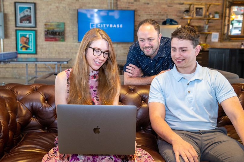 Citybase colleagues having a team huddle looking at a laptop