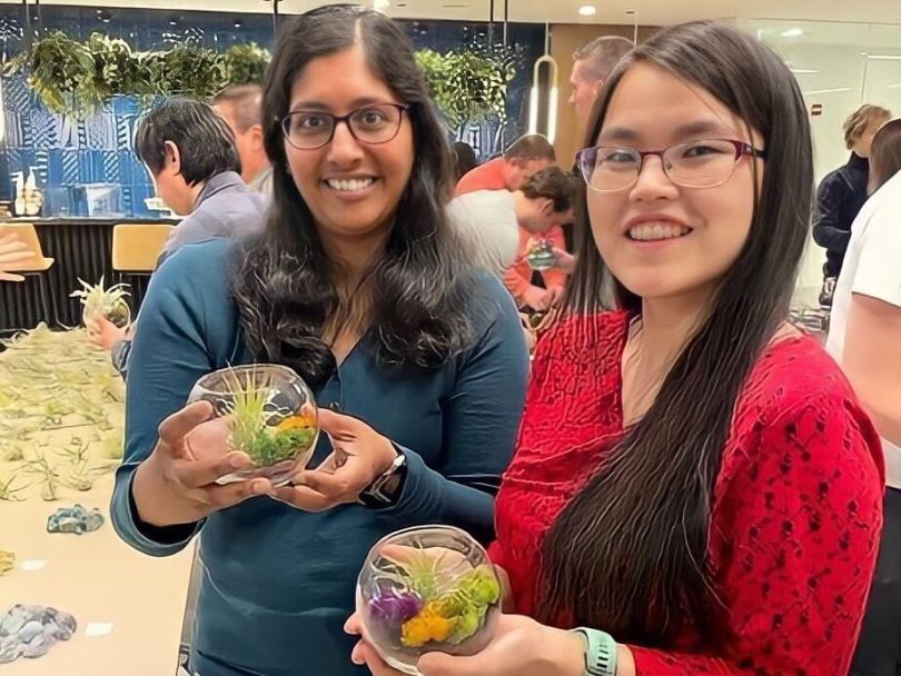 Two iManage team members holding succulent terrariums