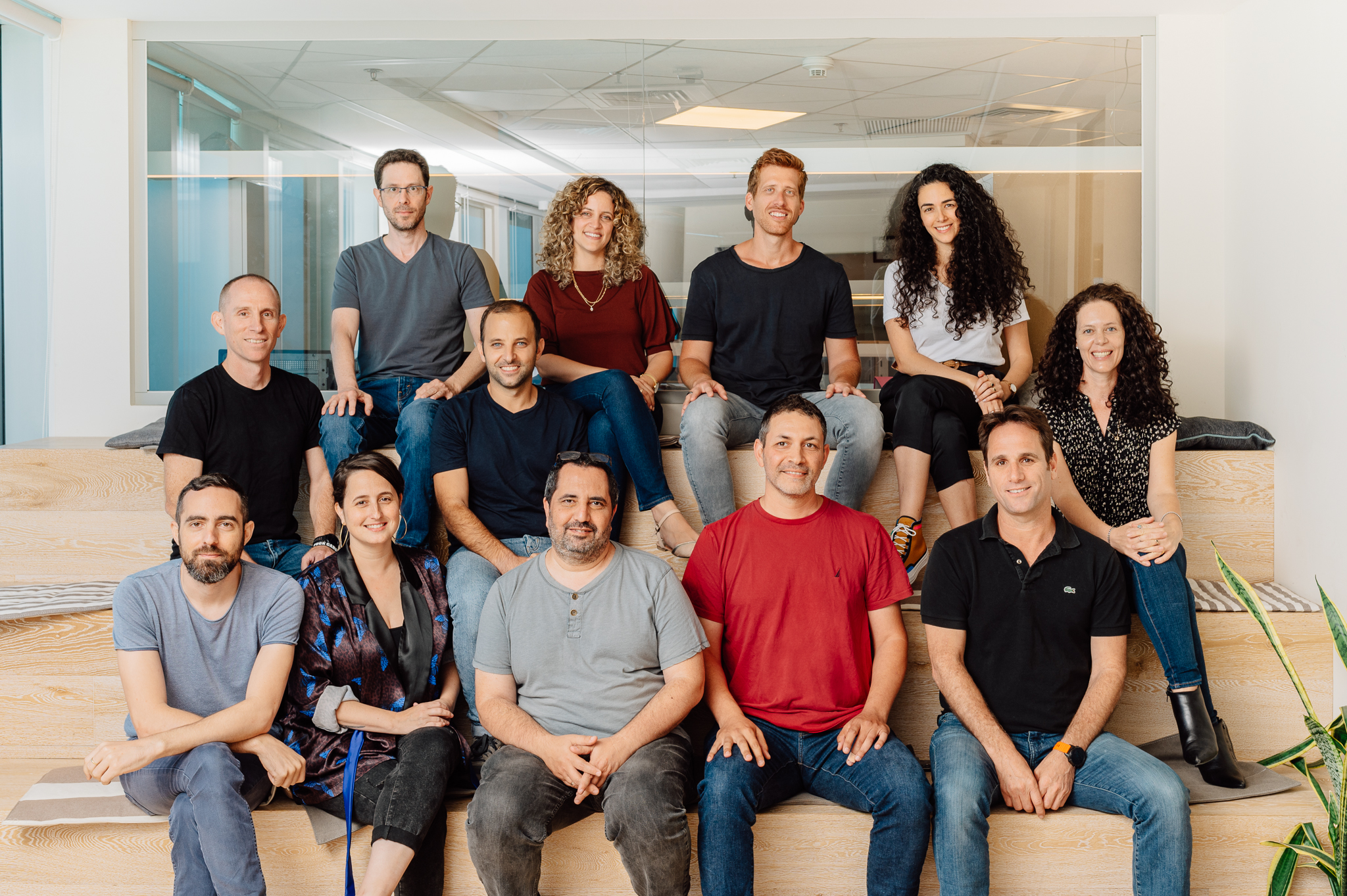 The Monday.com leadership team sits on benches in the office