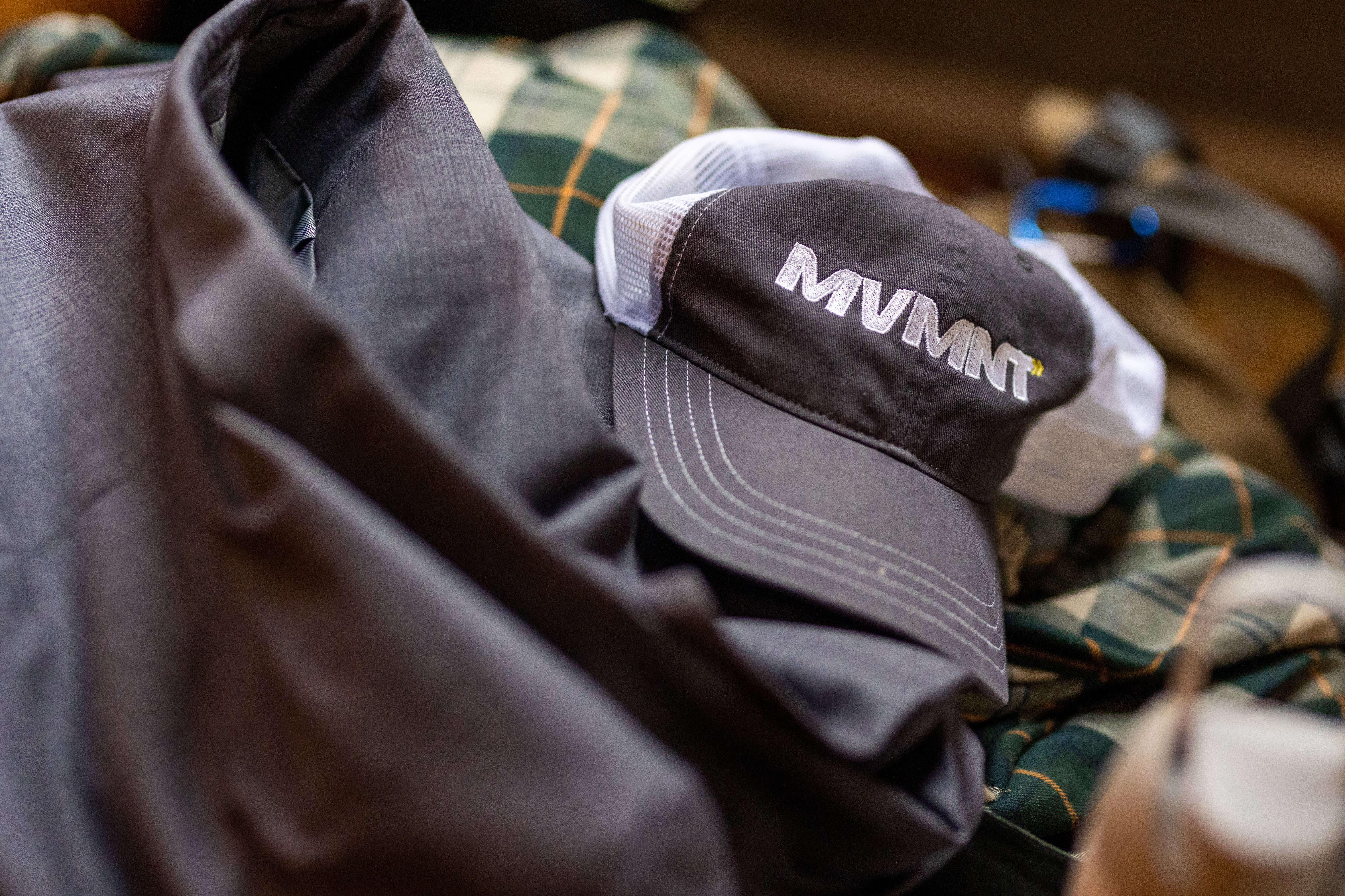 A MVMT branded trucker hat sits on a pile of clothes