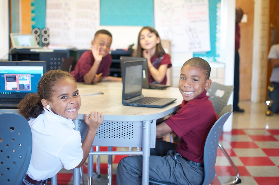 Students in classroom using laptops and smiling - Relativity, Wired to Learn grant