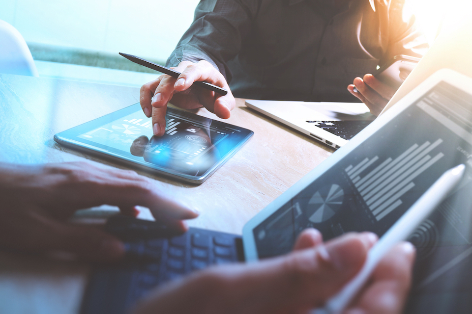 Two financial analysts working on mobile devices