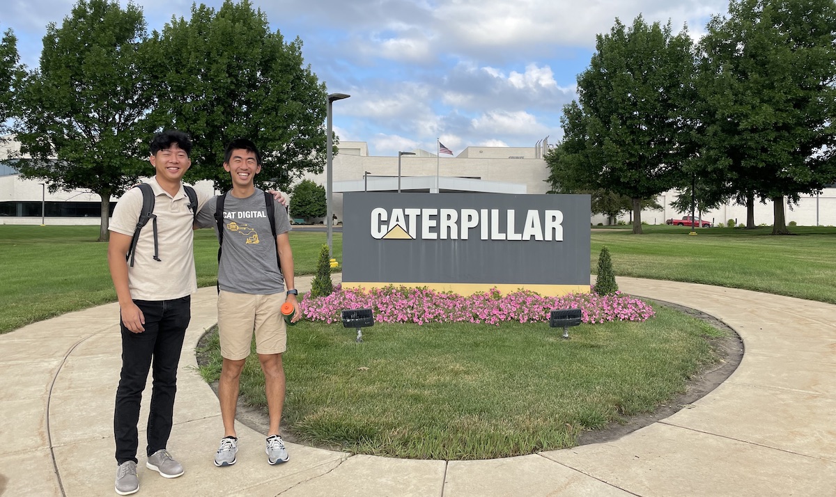 Two young men stand outside the Caterpillar office