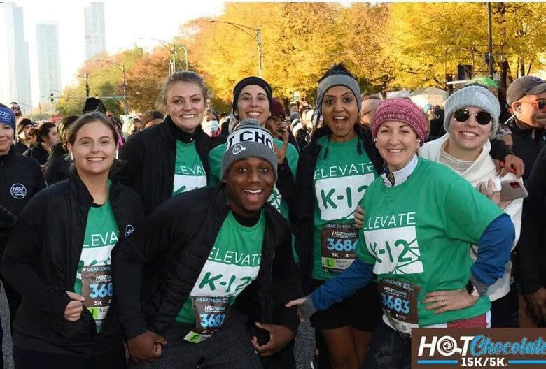 A group of Elevate employees smile together after participating in the Chicago Hot Chocolate Run.