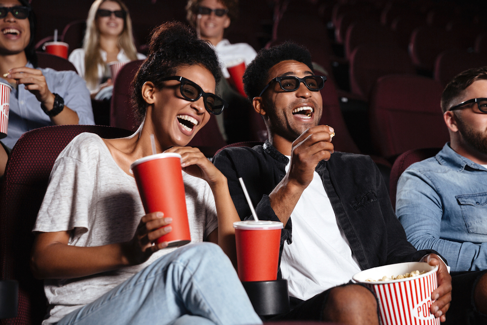 Couple wearing 3D glasses in a movie theater laughing 