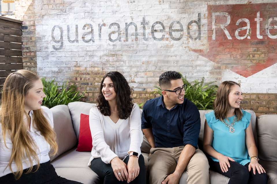 Employees of Guaranteed Rate chatting on sofa in office