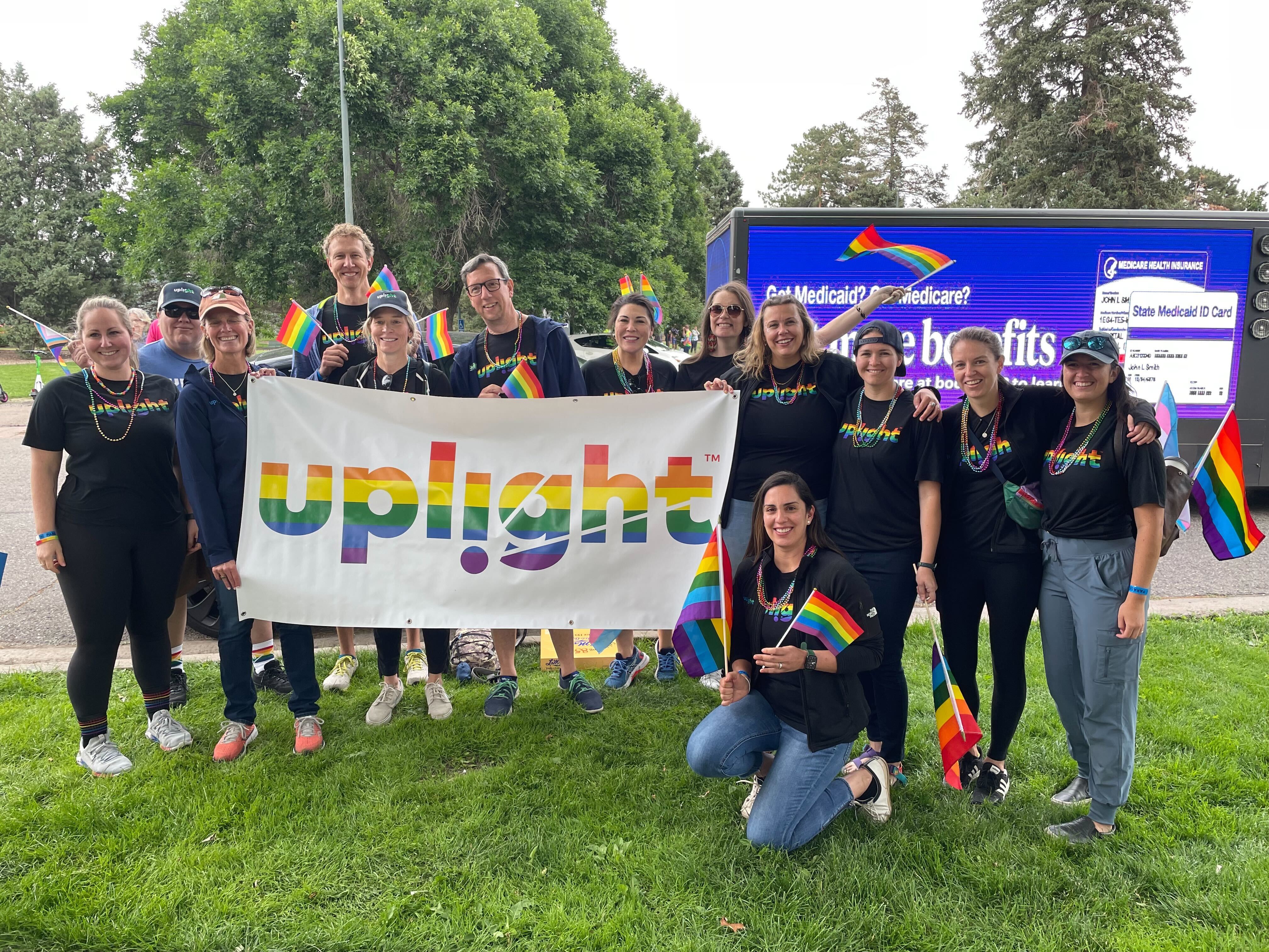 uplight team photo taken outside, with employees holding up banner with company name