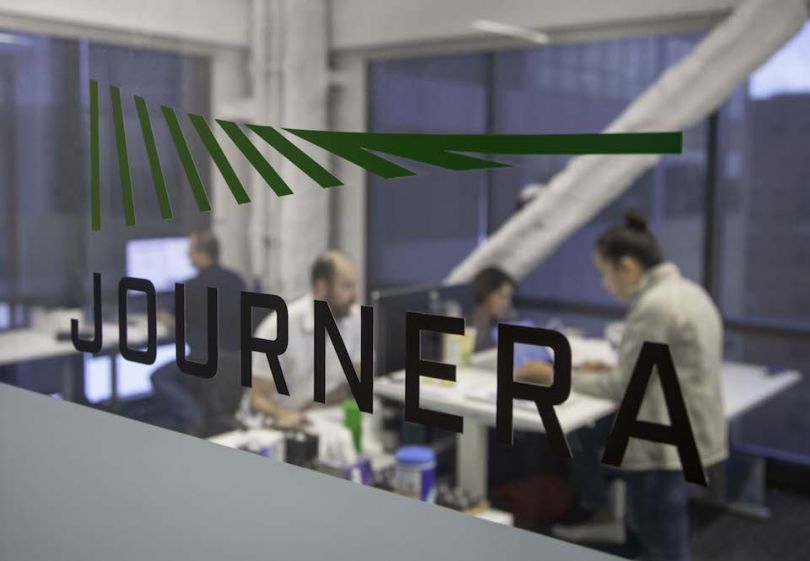 Journera's logo in their Chicago office with employees in background
