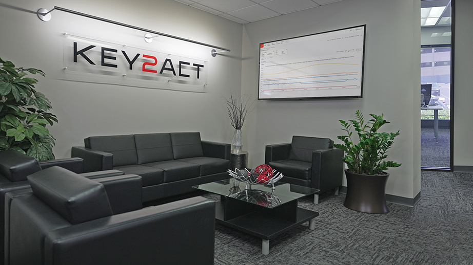 Sitting area in the Key2Act office with the company logo on the wall