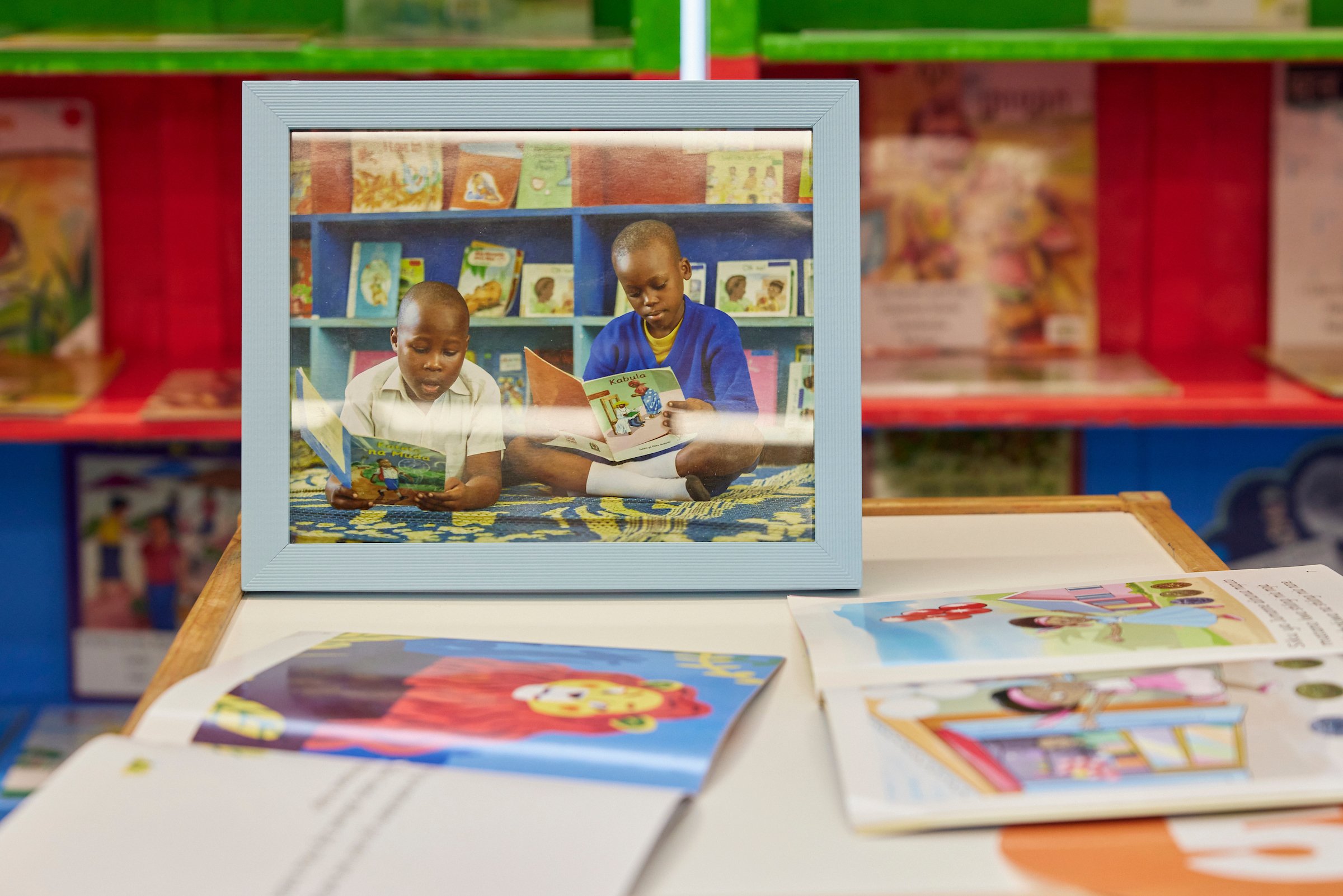 A framed photo of children reading provided by Room to Read sits on an IMC Trading table. 