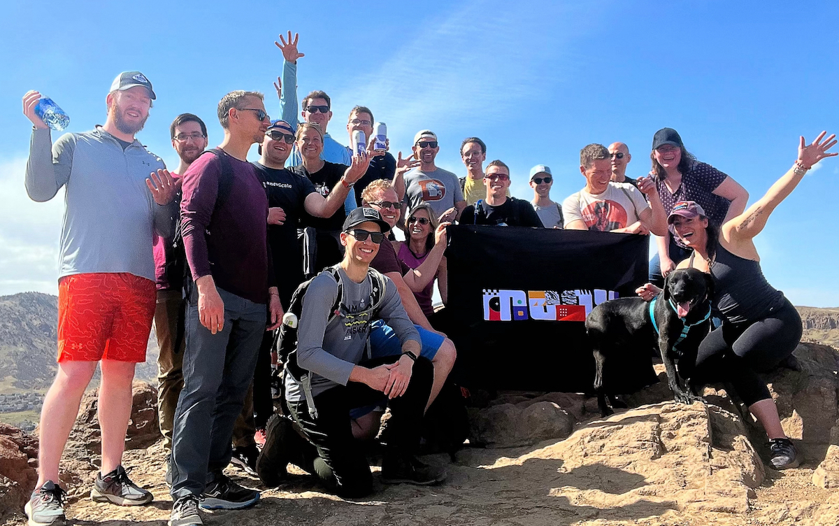 Members of the Moov team hold a Moov flag at the top of a mountain