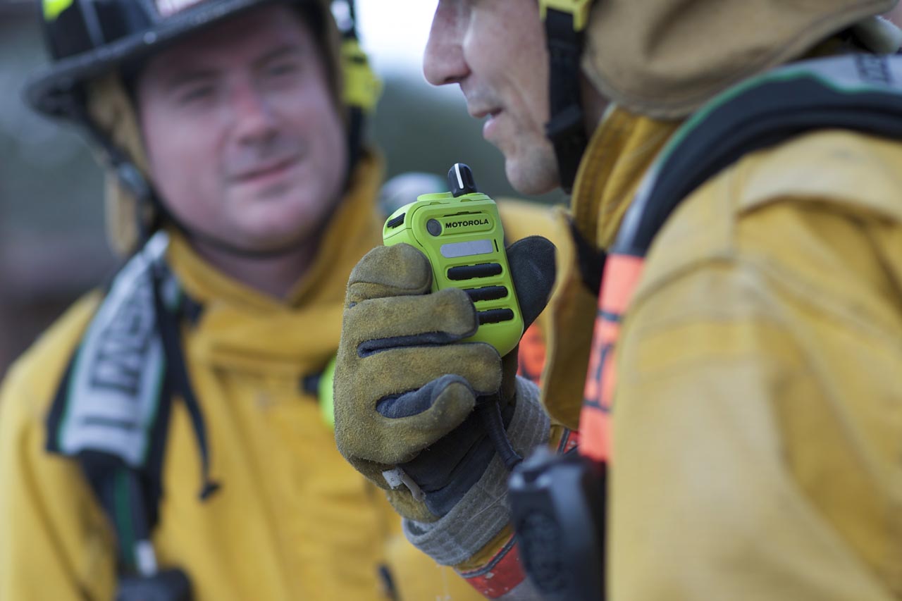 Fireman holding a yellow Motorola radio.