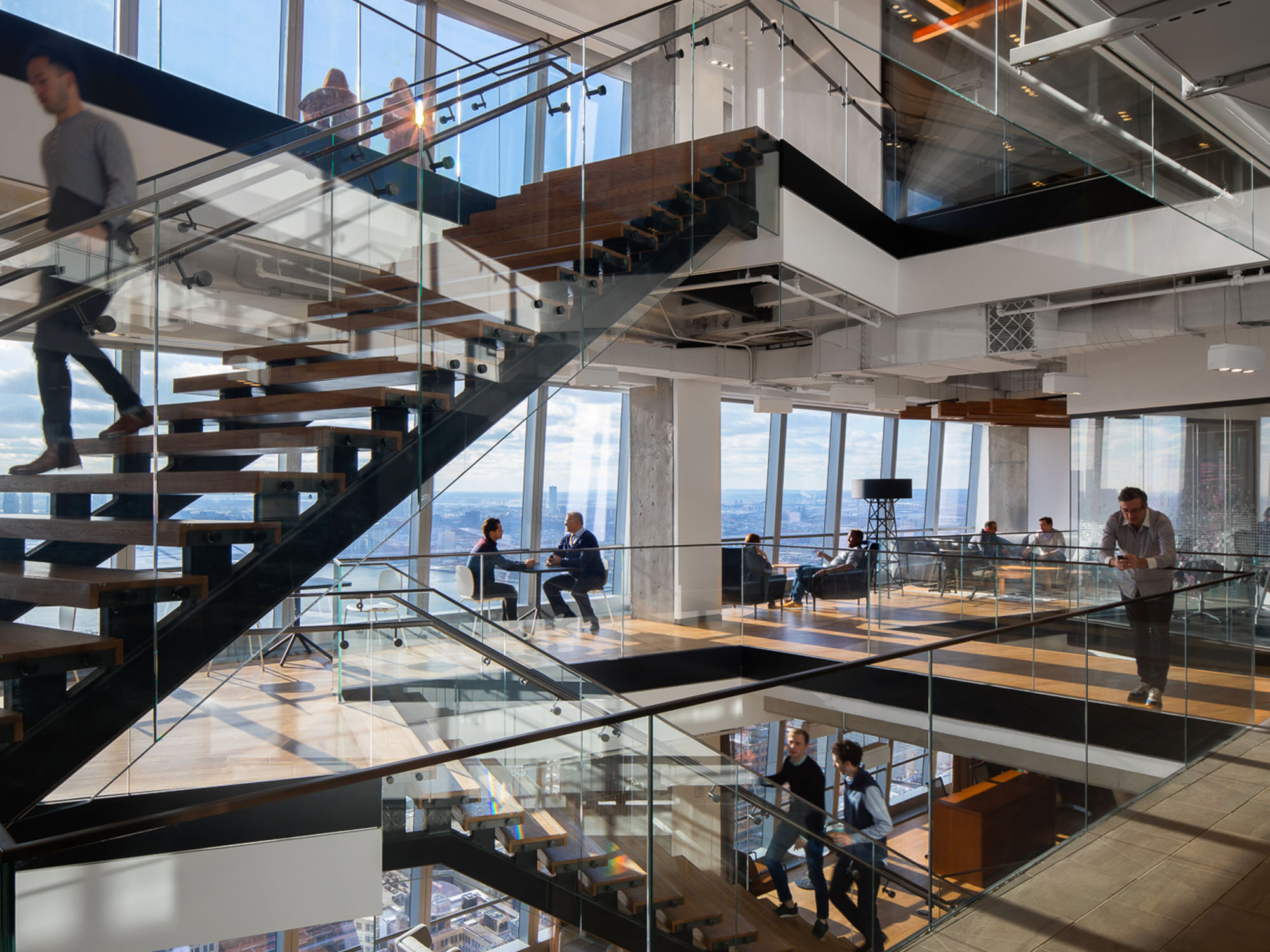 NYC office interior with walls of windows and staircase between levels