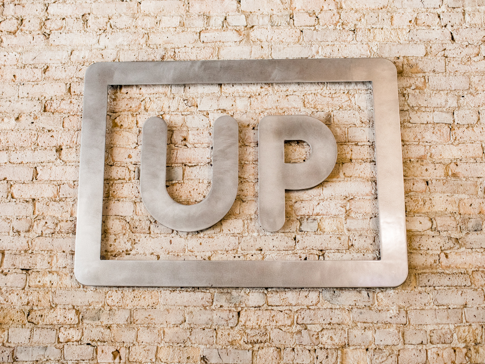 UPShow logo displayed on a brick wall