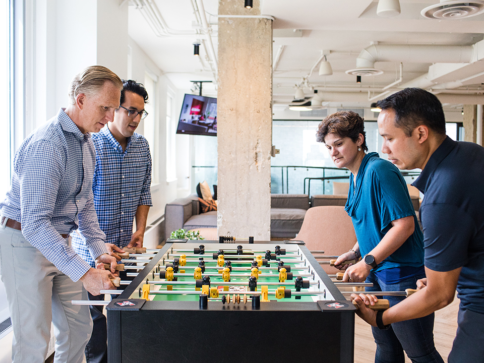 Scott Clements plays foosball with employees in the OneSpan office