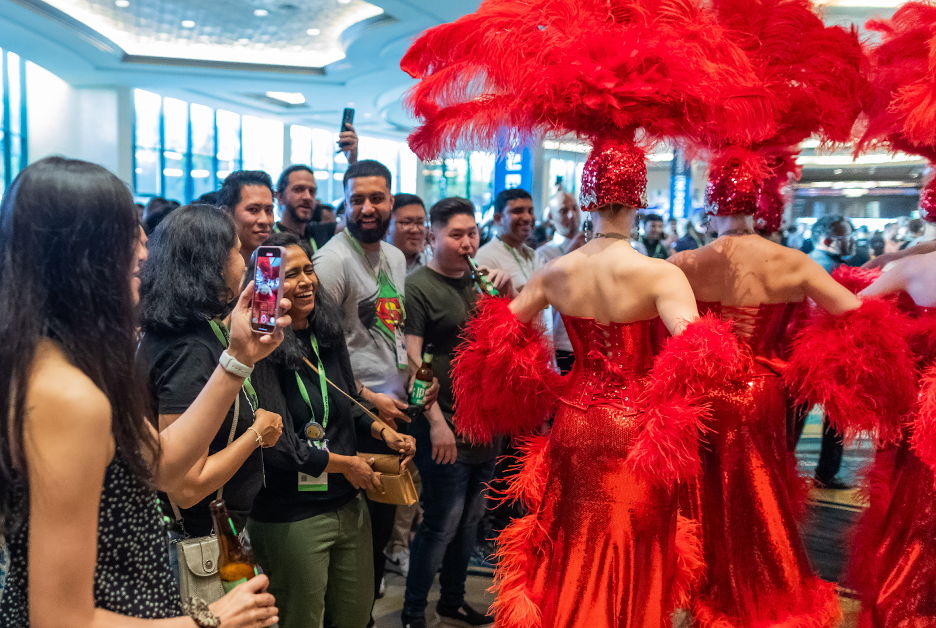 ServiceNow employees taking photos of dancers in red feathered costumes at UTG Connect.