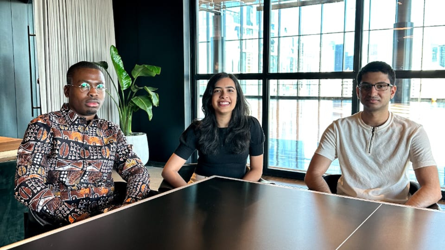 Rivet co-founders Anj Fayemi, Simran Pabla and Saad Rahman sit around a table in an office.