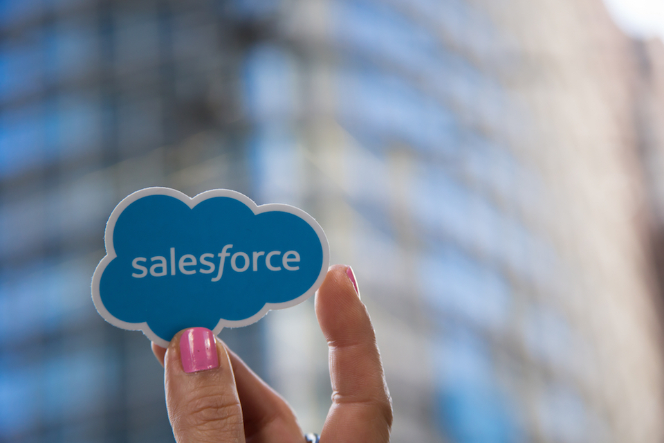 Salesforce logo being held up by woman's hand painted pink