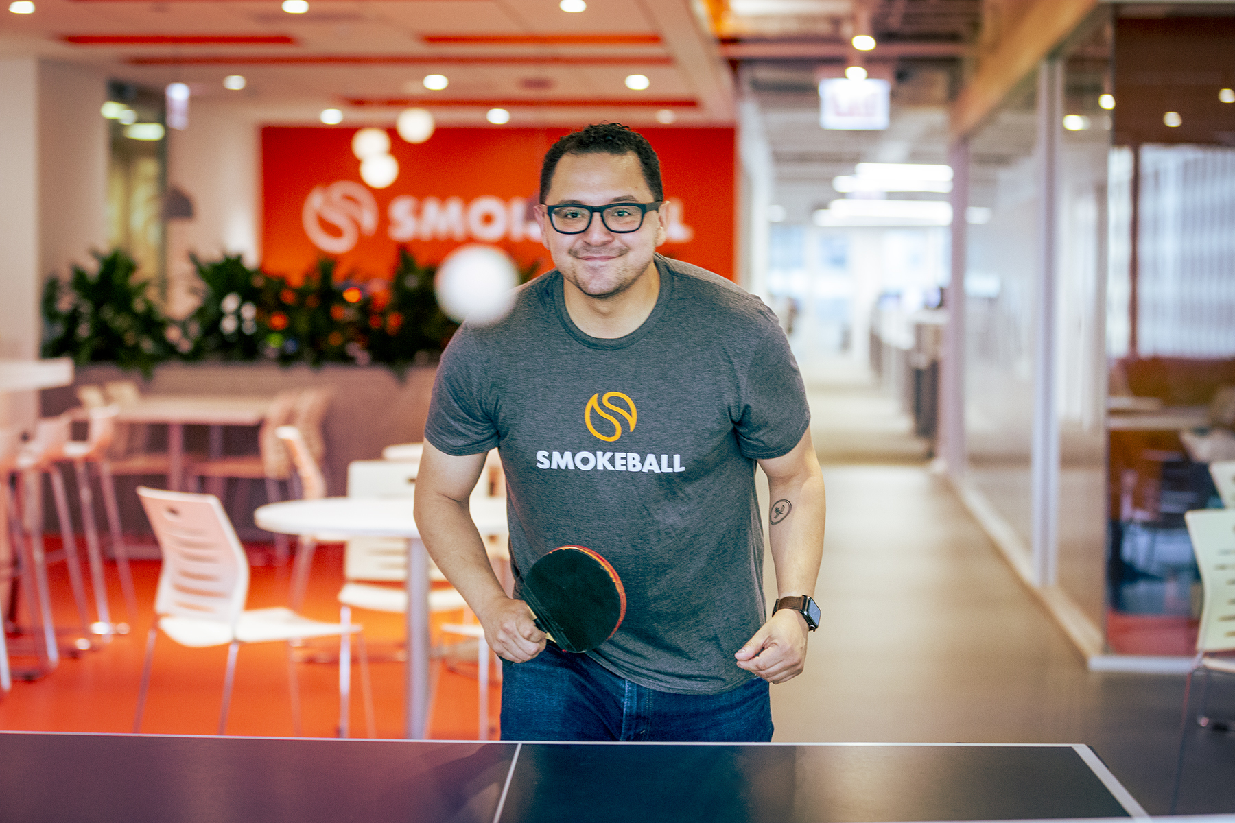 Employee at Smokeball plays ping pong in the office