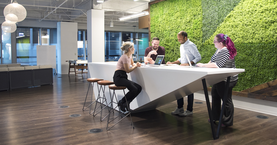 Three Sprout Social team members chatting in front of floral wall