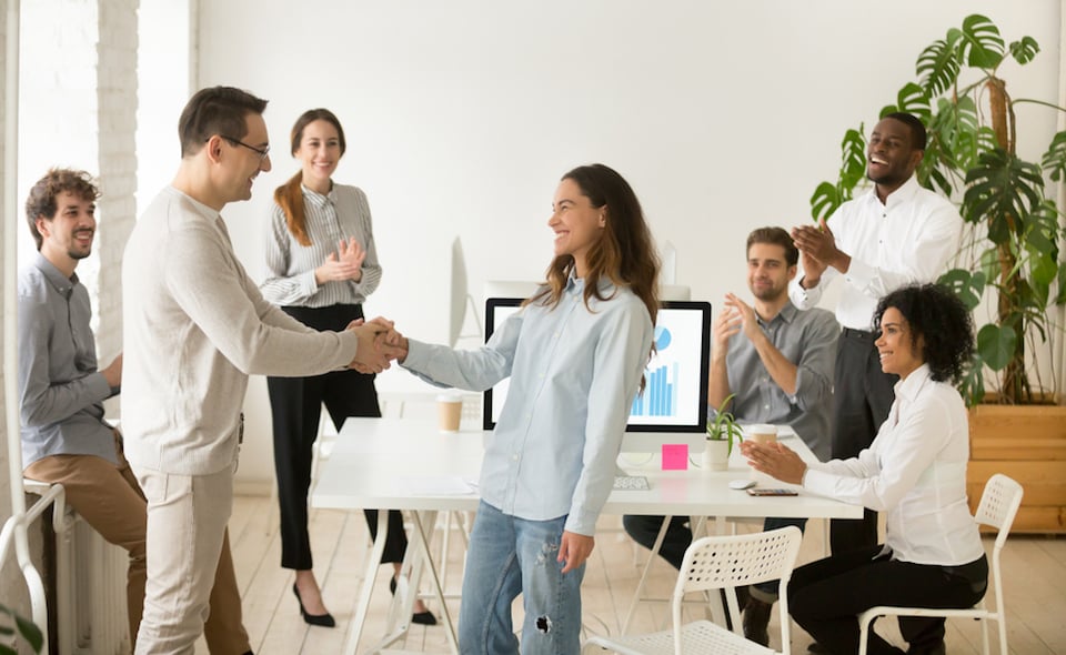 Team members in office congratulating new hire