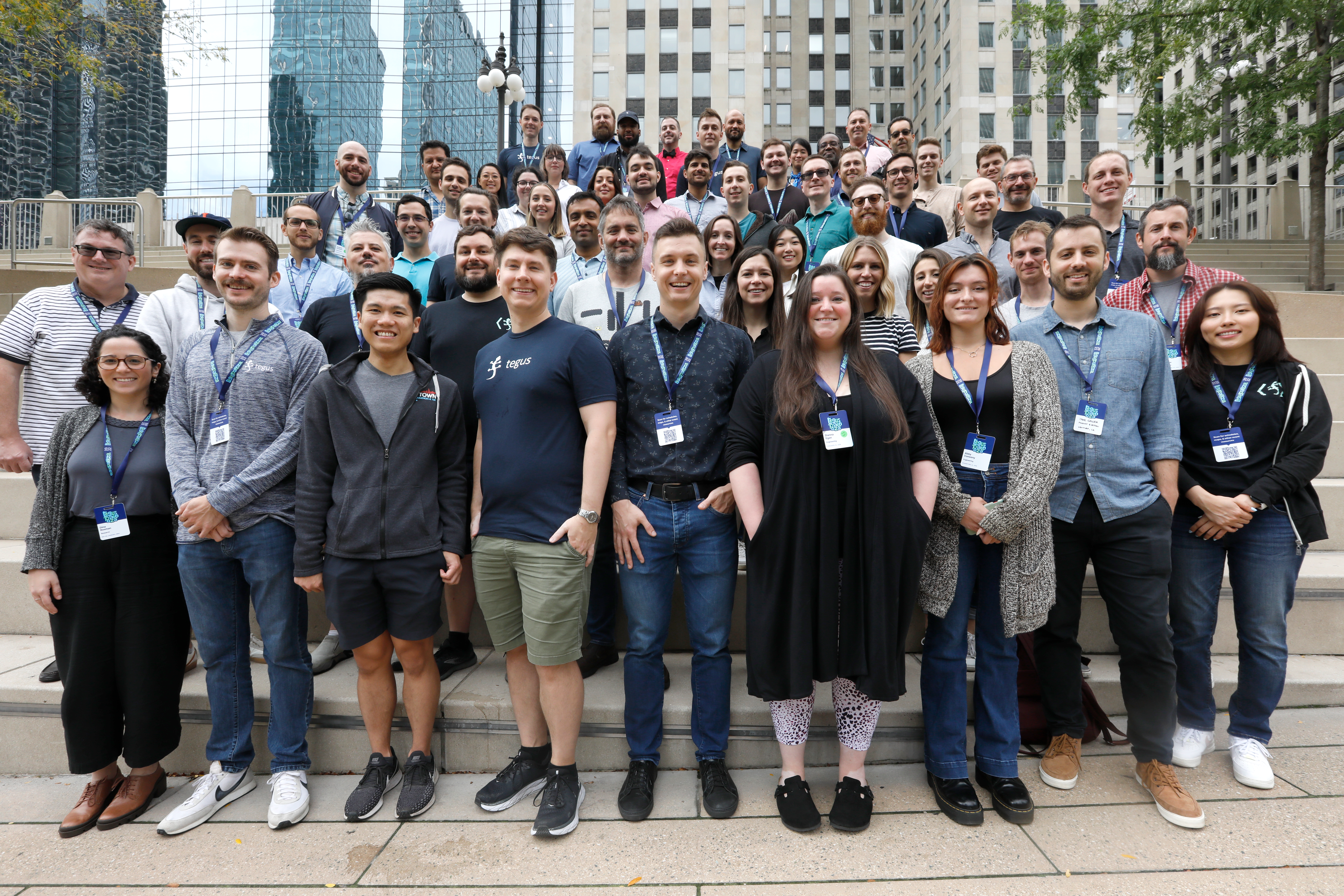  Large group photo of Tegus team on outdoor steps amid city buildings. 