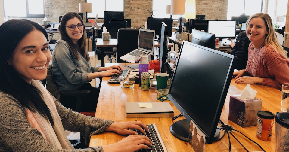 The Mom Project team members smiling at their desks