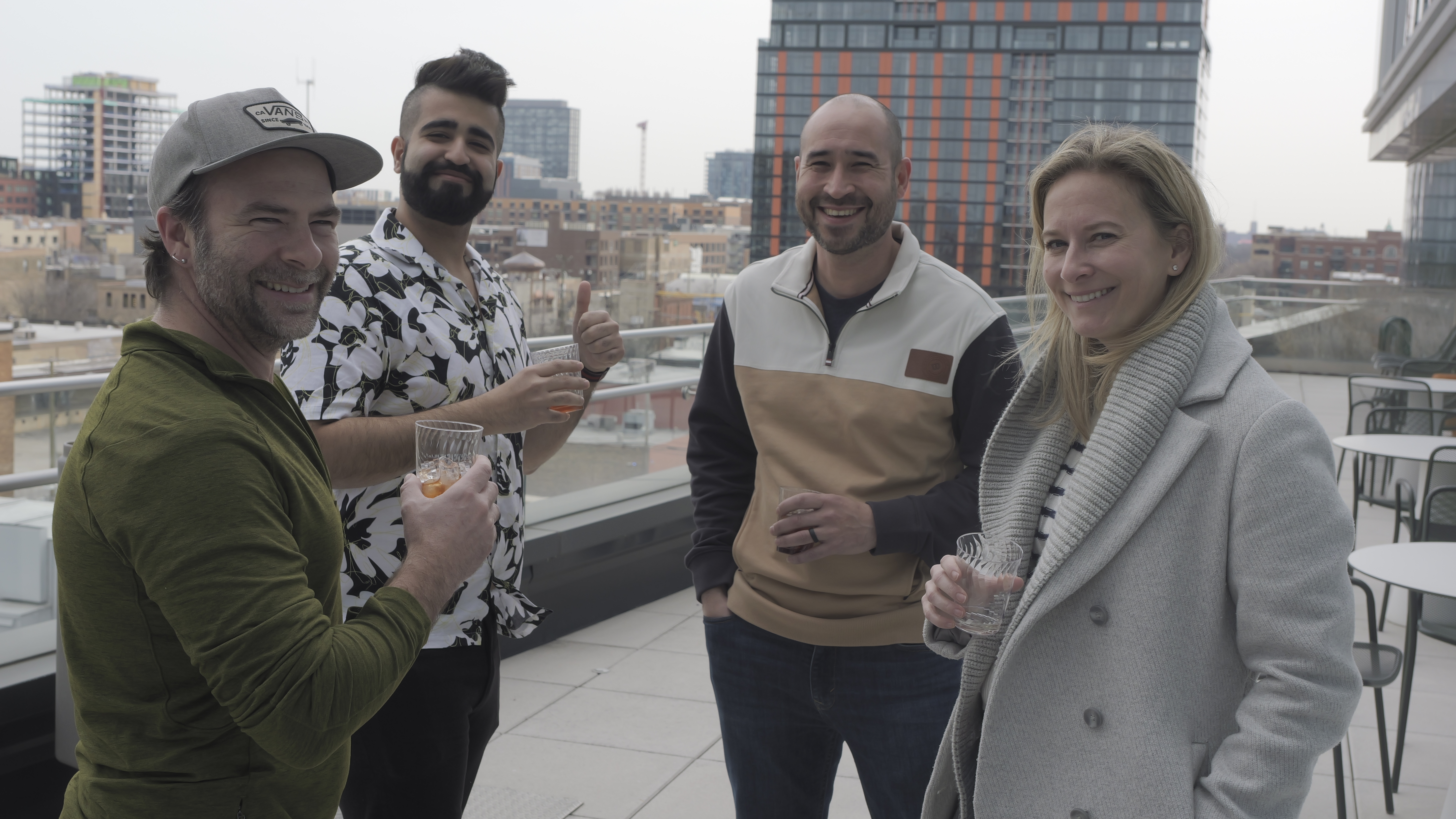 Four employees gathered on rooftop terrace, smiling