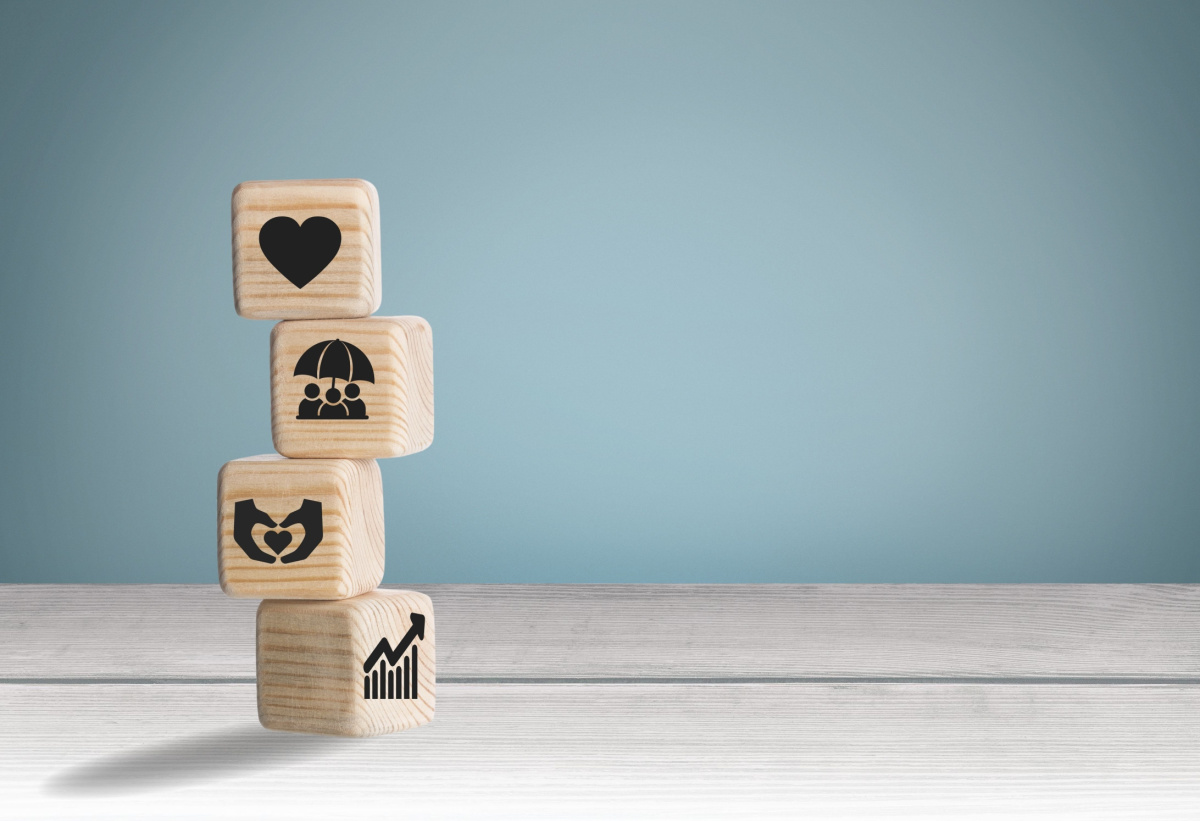 Wooden blocks stacked with symbols depicting various elements of employee benefits. 