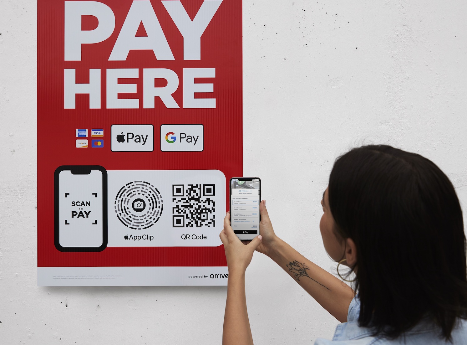 A woman uses her phone to scan one of FLASH’s Scan to Pay signs, WHICH ALLOWS USERS TO PAY USING APPLE’S APP CLIP AND QR CODE TECHNOLOGY. 