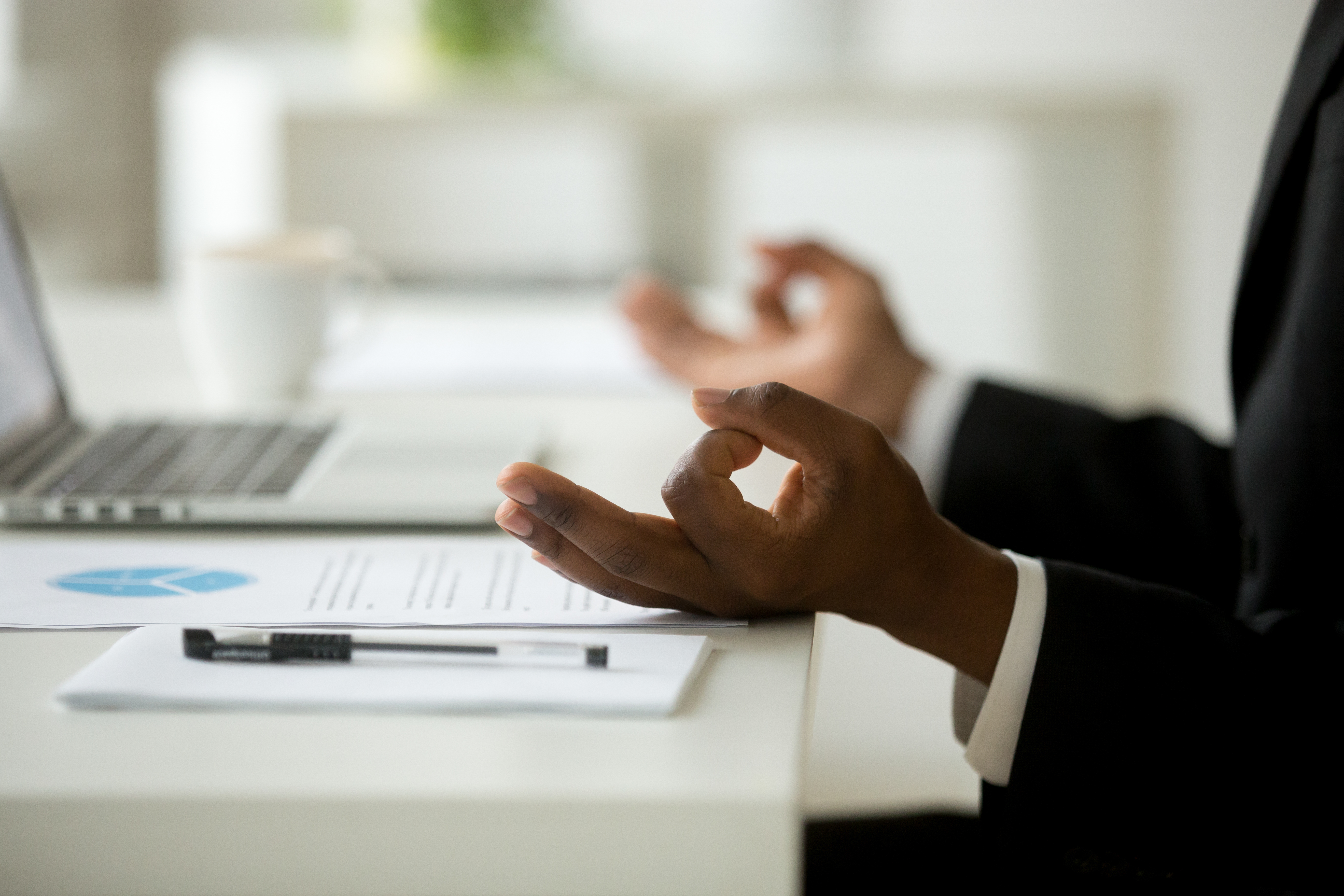 A male employee meditates at the desk.