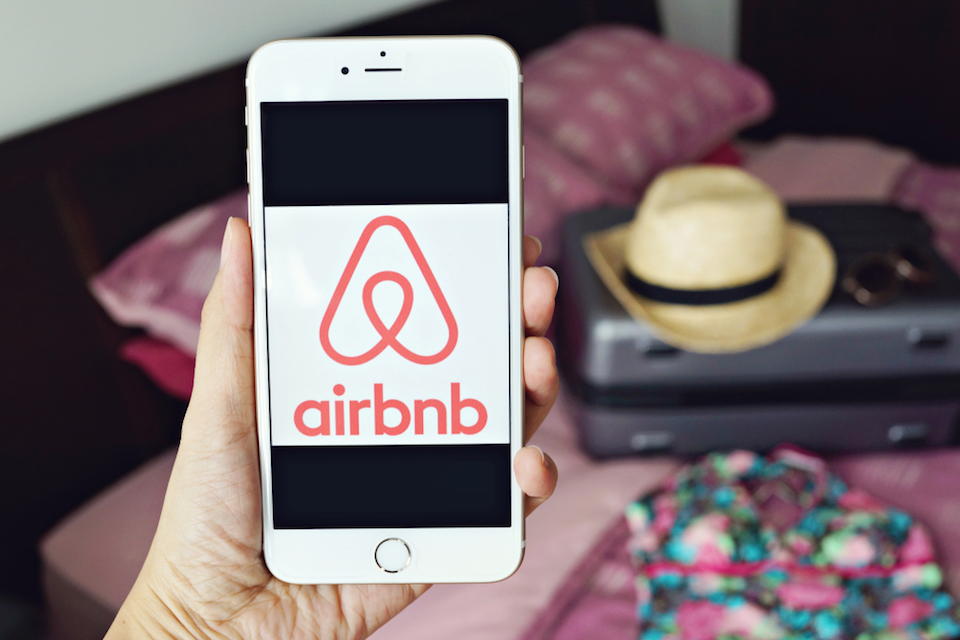 Person holding phone with Airbnb logo