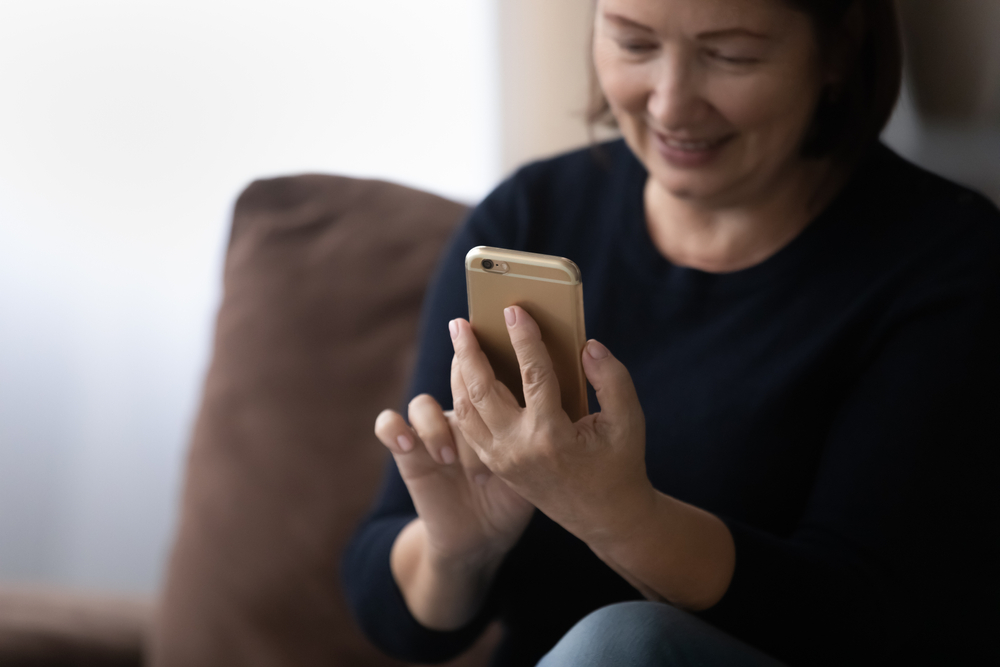 Woman using smartphone for telehealth treatment.