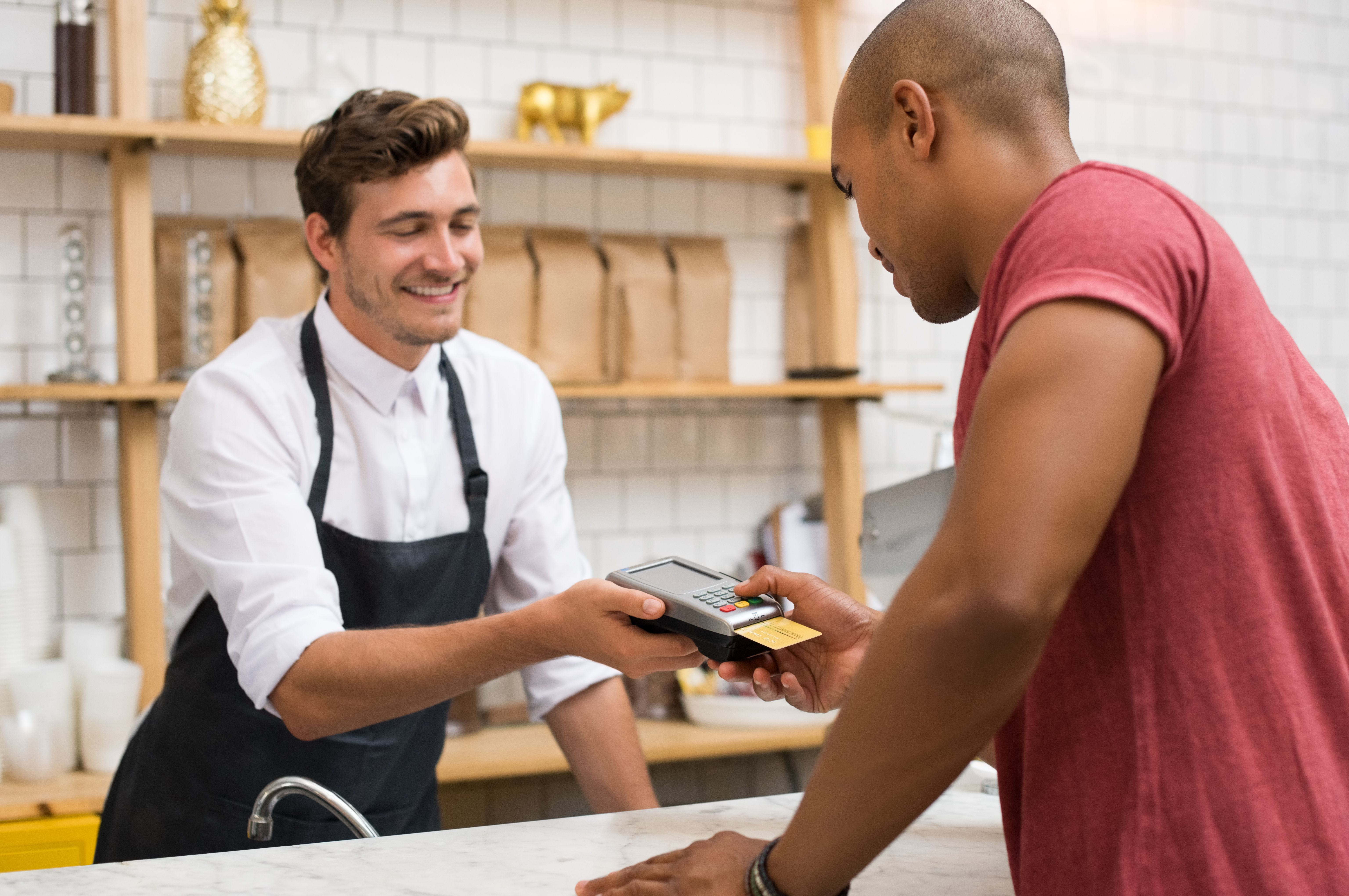 stock photo of store owner holding out credit card machine for customer to pay