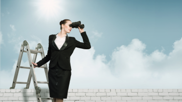 A businesswoman stands on a ladder holding binoculars.