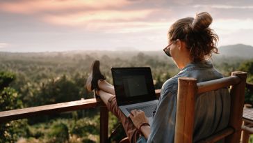 A woman works on her laptop overlooking the jungle.