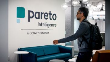 Pareto logo on the wall in the office with a team member walking by