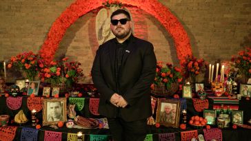 CASHDROP founder and CEO Ruben Flores-Martinez stands in front of a Día de Muertos alter
