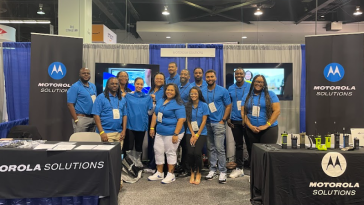 Part of the Motorola Solutions team posing at a company booth.