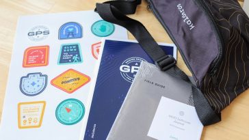 Photo of Kalderos swag featuring a bag, stickers, a GPS document and a “Field Guide” book.