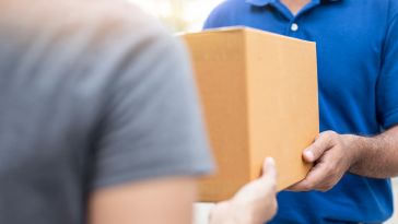 A person is pictured handing someone a box.