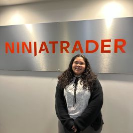 Maria standing in front of the NinjaTrader logo